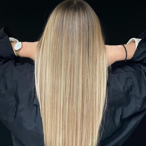 Back of woman’s head with long, super-straight, neutral blonde hair and balayage.