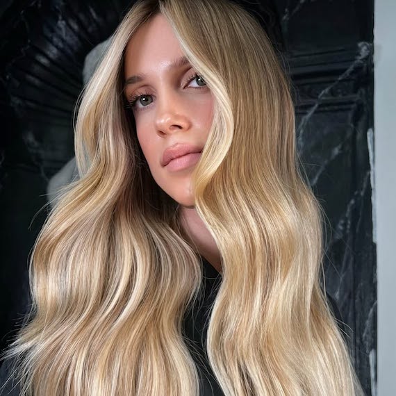 Model with long, honey blonde, wavy hair featuring a lighter face frame.