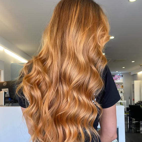 Model with ultra-long, wavy, strawberry blonde hair.