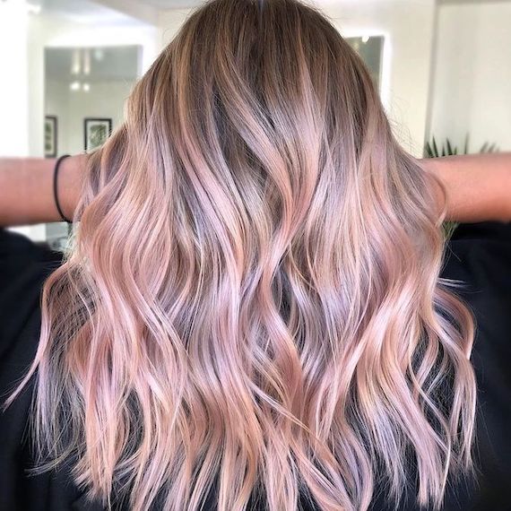 Back of model’s head with long, wavy, blonde hair and pastel pink balayage.
