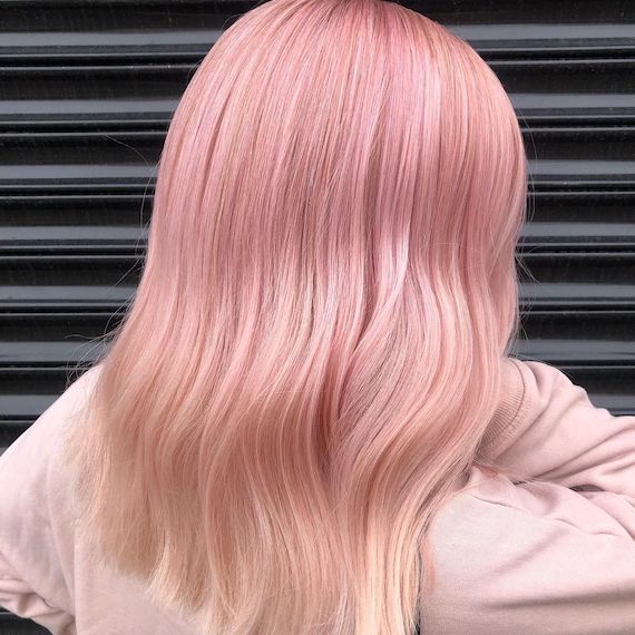 Back of model’s head with mid-length, straight, pastel pink ombre hair.