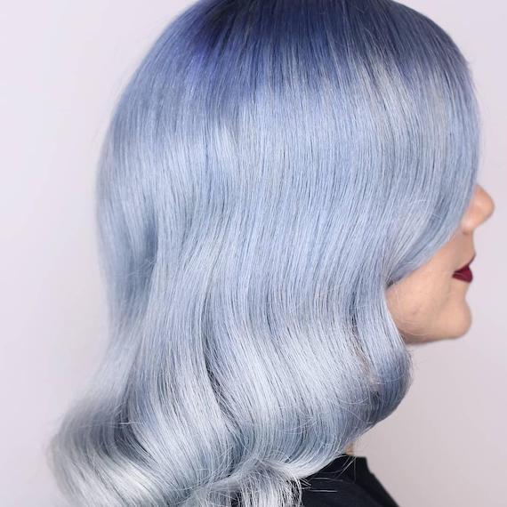 Side profile of model with blow-dried, pastel blue ombre hair.
