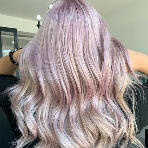 Back of woman’s head with long, wavy, hair and pastel pink highlights