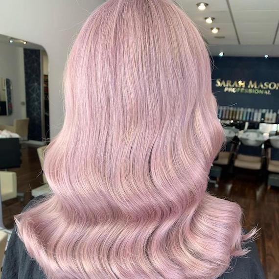 Hinterkopf einer Frau mit langem, gewelltem, lila-rosa Haar, kreiert mit Wella Professionals.