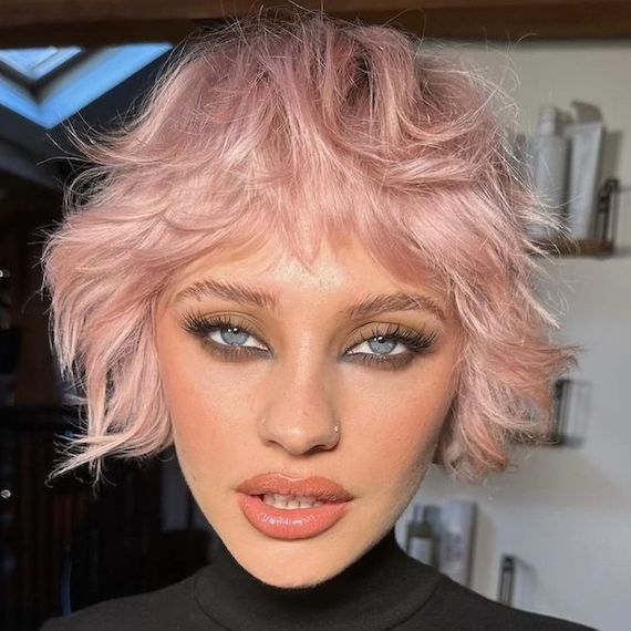 Model with shaggy, micro bob haircut that’s been dyed pastel pink.