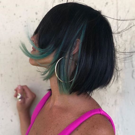 Side profile of woman with dark brunette bob and peekaboo peacock hair, created using Wella Professionals.