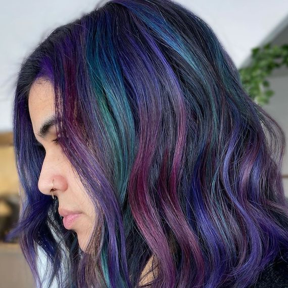 Side profile of woman with long, dark brunette bob and peacock hair color, created using Wella Professionals.