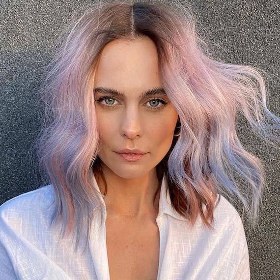 Model mit pastellrosa Haaren und puderblauem Balayage in die Kamera.