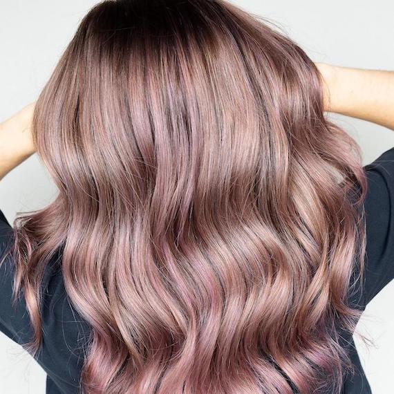 Back of woman’s head with long, ash brown hair and hints of pink balayage.