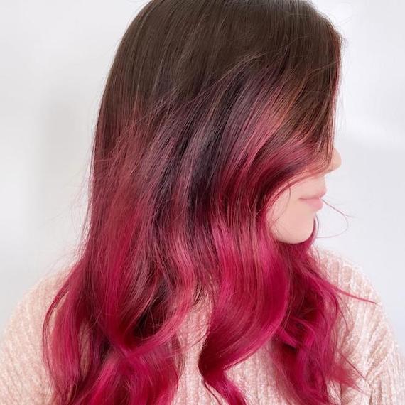 Side profile of woman with dark brown hair and hot pink balayage.