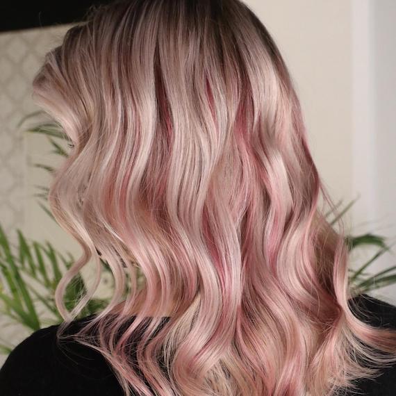 Back of woman’s head with blonde, tousled hair and candy pink balayage.