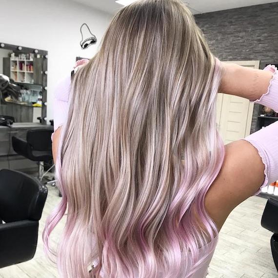 Hinterkopf einer Frau mit langen, glatten, blonden Haaren und rosa Spitzen, kreiert mit Wella Professionals.