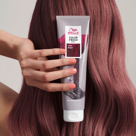 A person holding a bottle of Color Fresh Mask in shade Rose Blaze behind their head