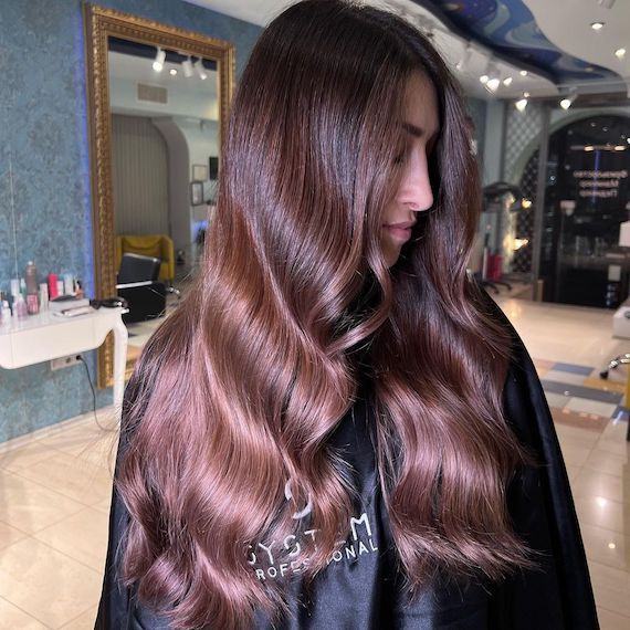 Model looks to the side to show off long, brunette and rose brown ombre hair. 
