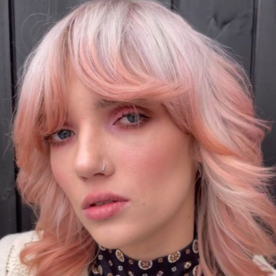 Model with blonde and pink ombre hair looks into the camera.