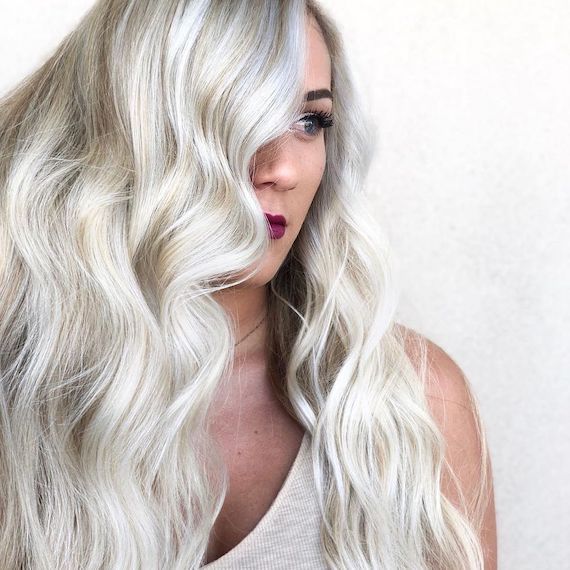 Model with beachy platinum blonde waves gazes to the side. 