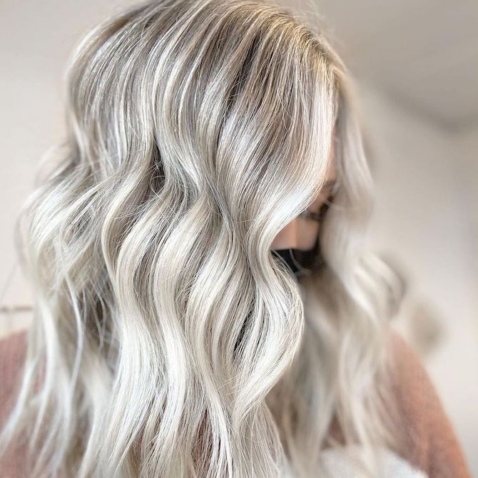 Model with dimensional, platinum blonde highlights through wavy hair.
