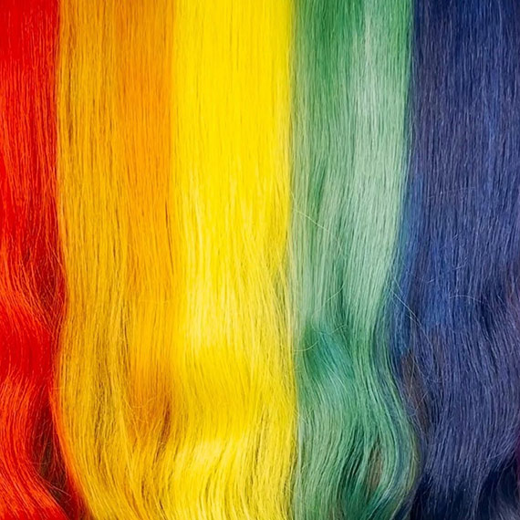 A close-up of a model’s rainbow hair, representing the original Pride flag.