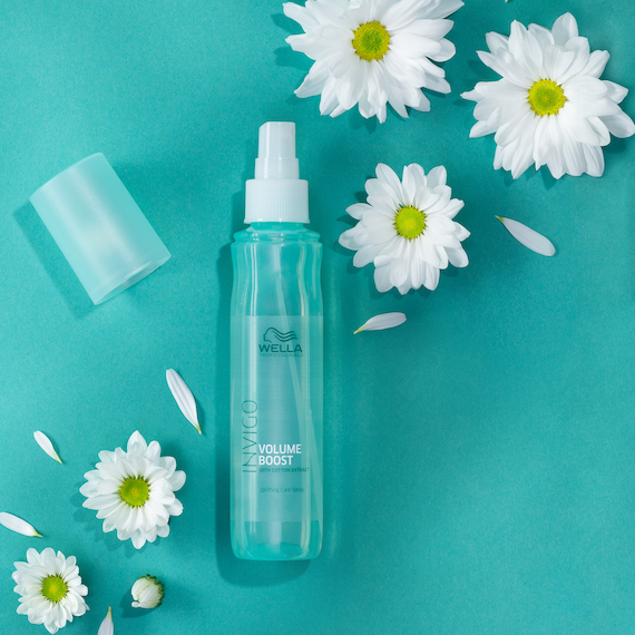 INVIGO Volume Boost Uplifting Care Spray on a green surface, surrounded by daisies.