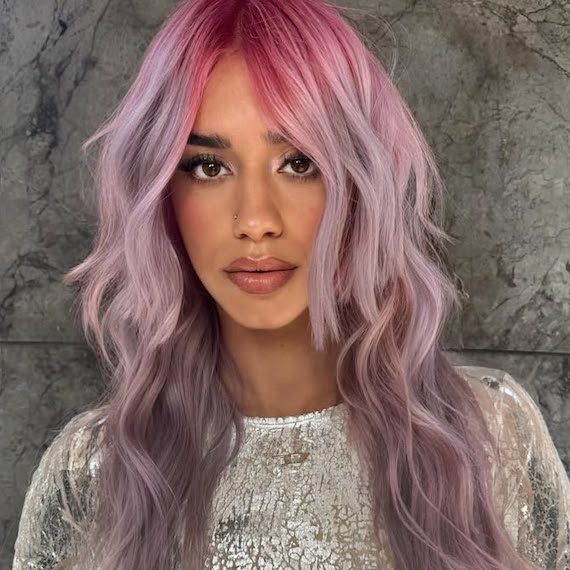 Model with pink to purple ombre hair styled in loose waves.