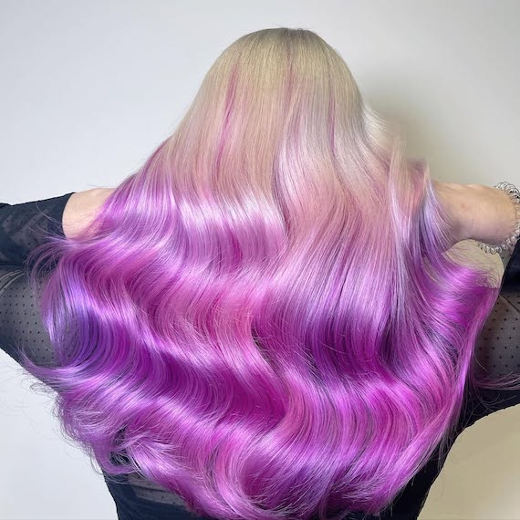 Back of model’s head with platinum blonde hair featuring vivid pink and purple colours through the lengths and ends.