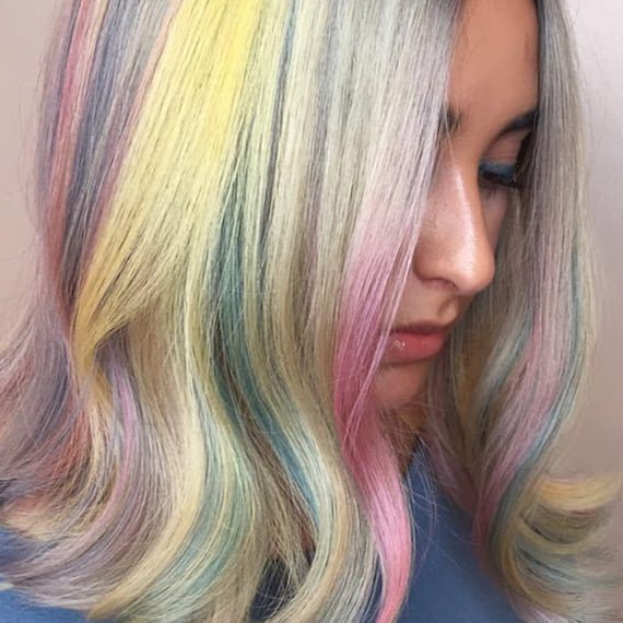 Woman from a side angle, wearing hair loose with pastel rainbow hair shades.