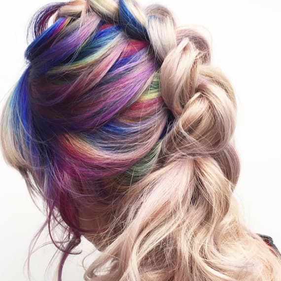 Image of the back of a woman’s head wearing ice blonde rainbow hair color in a reverse French braid, showcasing all shades. Look created by Wella Professionals.
