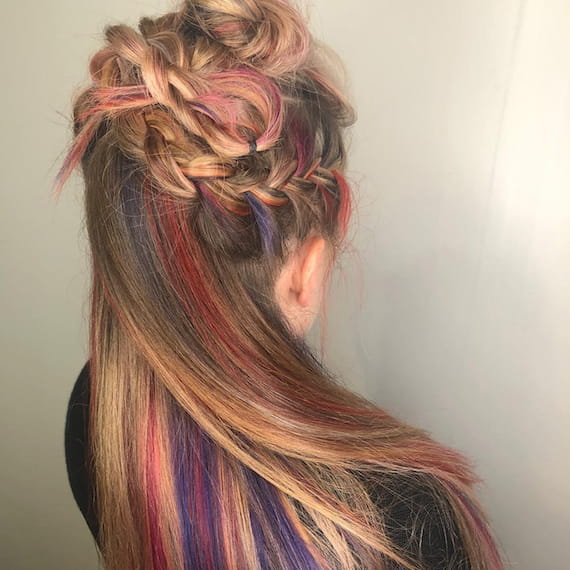 Image of the back of a woman’s head, with a half-up braided ‘do and multi-tonal rainbow color blended through natural hair color. Look created by Wella Professionals.