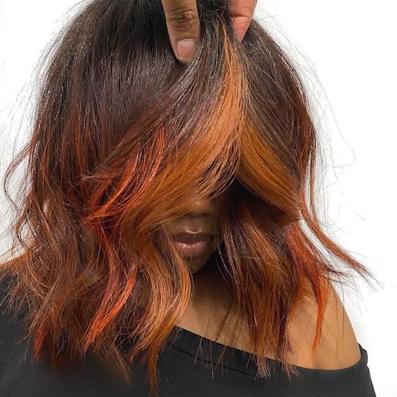 Headshot of a person with black and orange red balayage hair, colored using Koleston Perfect and Color Fresh CREATE by Wella Professionals.