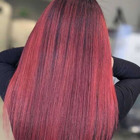 Back of a person’s head reveals their long, straight chili red highlights on black hair, colored using products by Wella Professionals. 