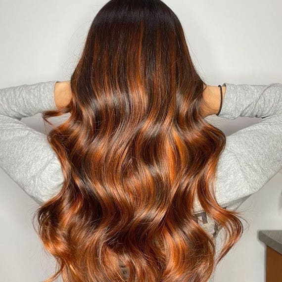 Back of woman’s head with long hair and red brown balayage, created using Wella Professionals.