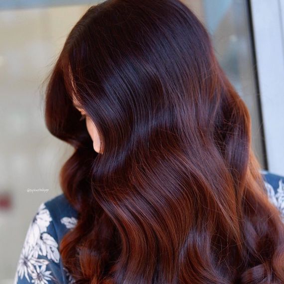 Side profile of woman with long, wavy, dark red brown hair, created using Wella Pro-fessionals.