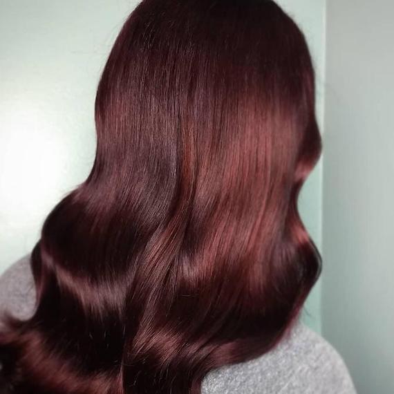 Back of person’s head with long, loosely curled, burgundy red hair.