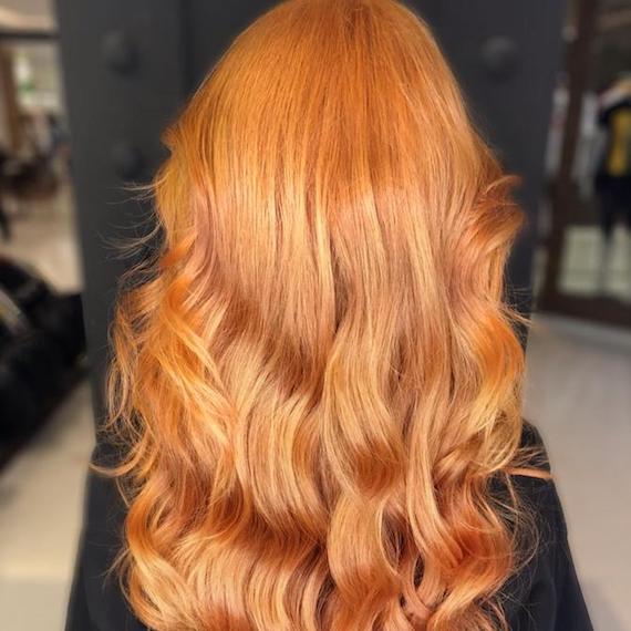 Photo of the back of a woman’s head with long, loose waves and ginger hair color, created using Wella Professionals.
