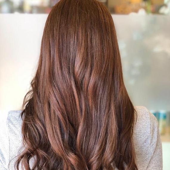 Photo of the back of a woman’s head with long, loose waves and auburn hair color, created using Wella Professionals.