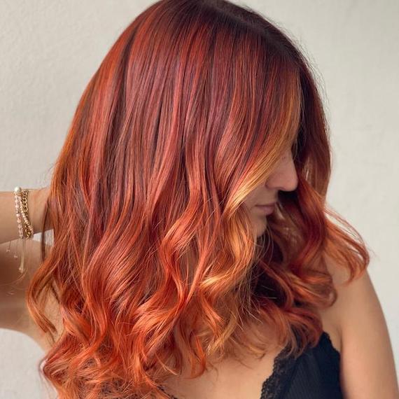 Side profile of woman with tousled red hair and a bronze blonde money-piece.