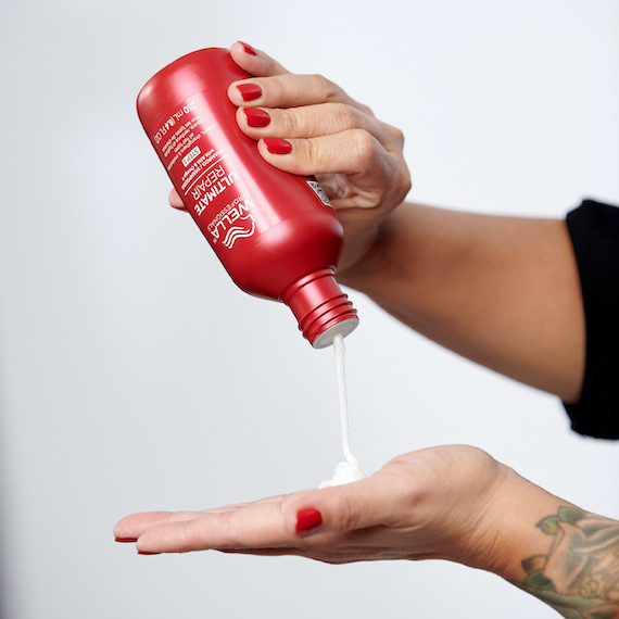 Eine Flasche Ultimate Repair Shampoo von Wella Professionals wird in die Handfläche einer Person gepresst