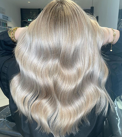 Silver blonde wavy hair that’s been colored and styled using a hair repair formula by Wella Professionals 