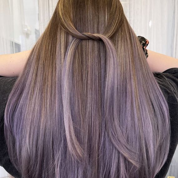 Person with dark blonde to lived-in lavender reverse ombre hair