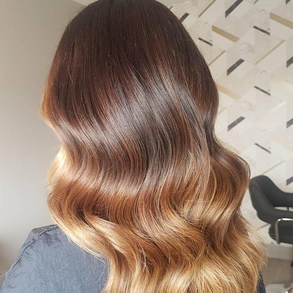 Back of woman’s head with golden blonde ombre and dark roots, created using Wella Professionals.