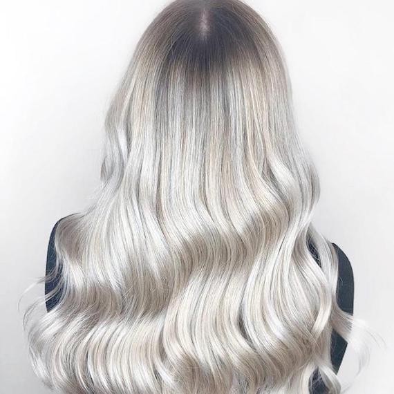 Back of woman’s head with ice blonde hair and a dark root shadow, created using Wella Professionals.