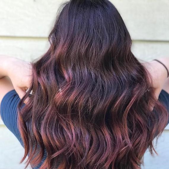 Back of woman’s head showing long, wavy hair with pink tones through the ends, created using Wella Professionals.