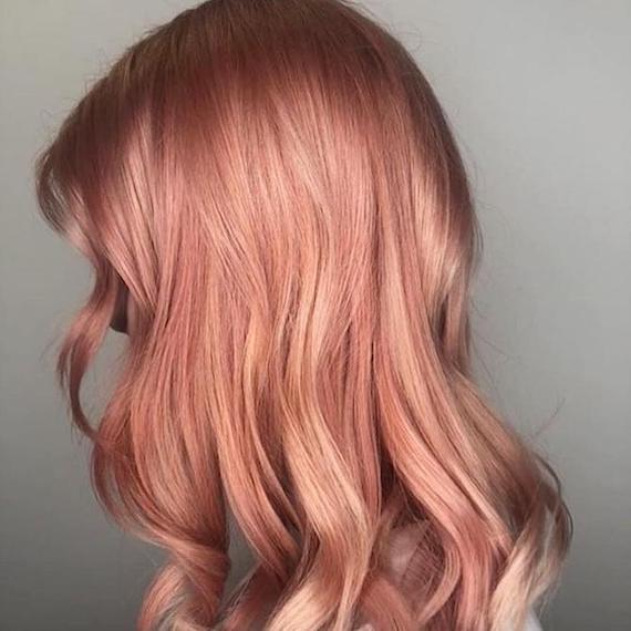 Side profile of woman with long, wavy rose gold hair, created using Wella Professionals. 