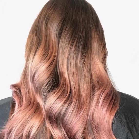 Back of woman’s head showing long, wavy rose gold ombre hair, created using Wella Professionals. 