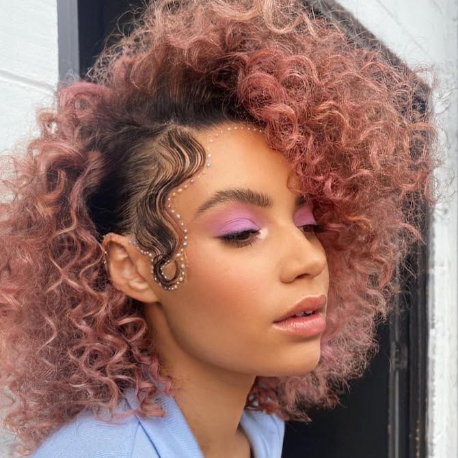 Model with dark, curly hair featuring a rose gold shade on the lengths and ends.