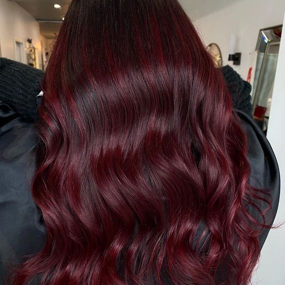 Close-up of deep ruby red hair that's styled in loose waves