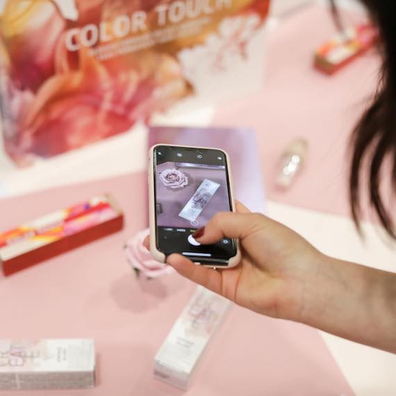 Woman taking flatlay photo on her phone of Wella Professionals products.