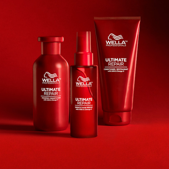 Wella Ultimate Repair Produkte von Wella Professionals stehen in einer Reihe auf einer roten Fläche