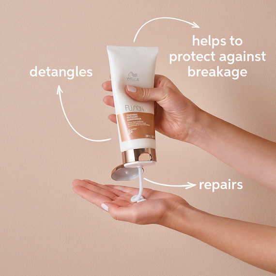 Nahaufnahme einer Person, die eine Flasche Wella Professionals Fusion Intense Repair in ihre Handfläche drückt 