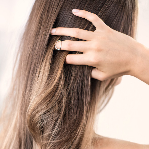 Back of a person's head. They are running their hand through their straight, light brown hair strands